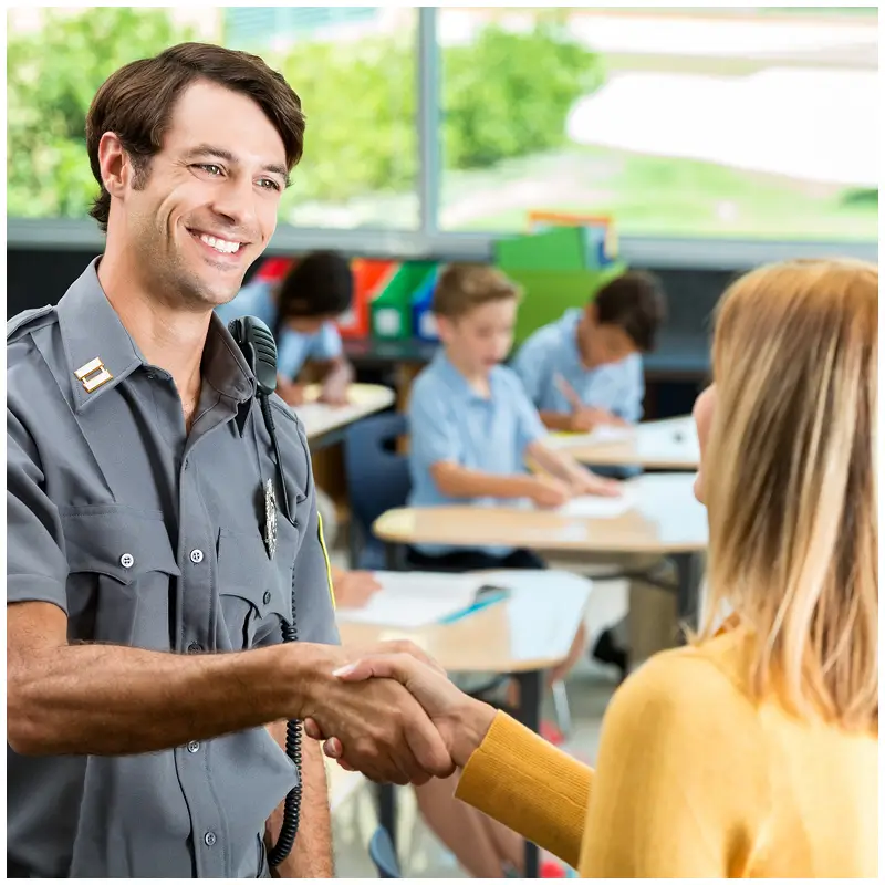 Police officer shaking hands with woman in classroom.